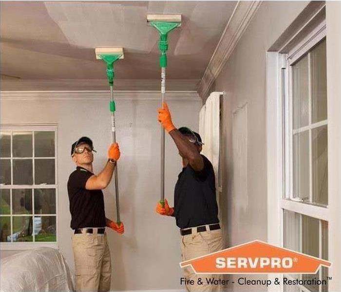 Two men cleaning a ceiling from fire soot