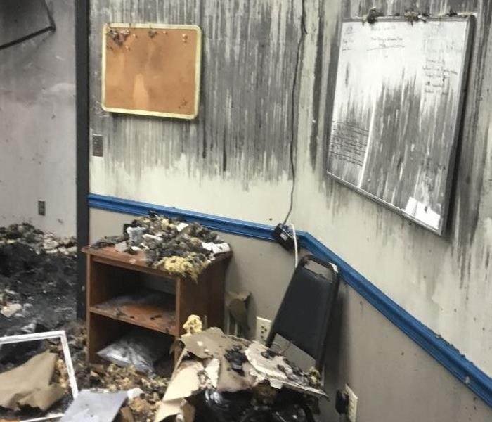 Two walls in an office with fire damage and burnt items