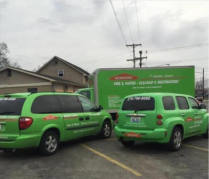 One truck box, two green vehicles, SERVPRO vehicle parked on a residential property