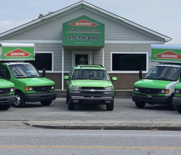 Here to Serve You. Image of SERVPRO vehicles outside of building.